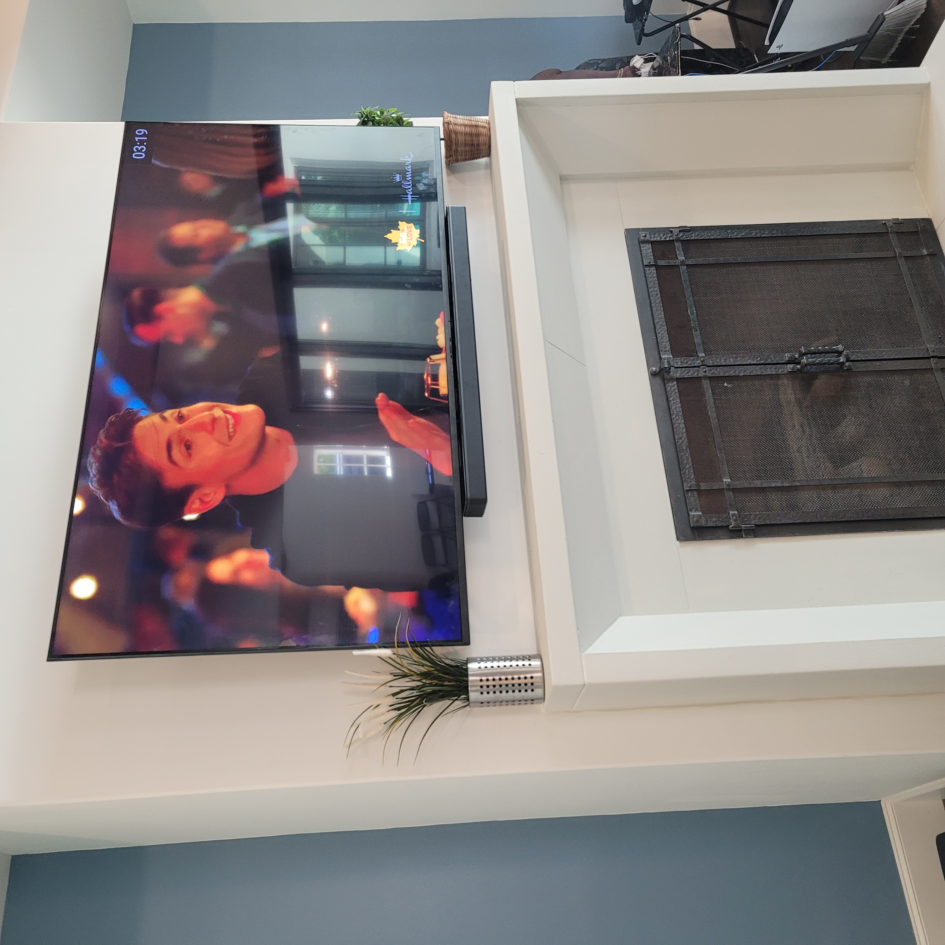 TV above traditional white fireplace surround with soundbar on mantle